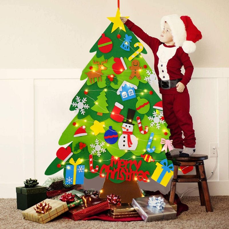 A 3-year-old boy dressed as Santa, standing on the stool, hanging an ornament on the top of the Montessori Christmas Tree.